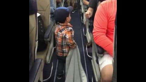 Kleine jongen begroet alle passagiers in het vliegtuig met een gettovuist