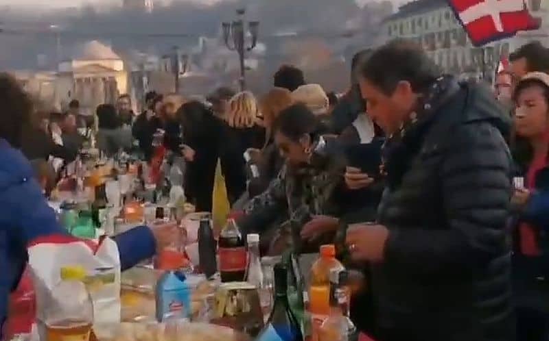 In Turin essen viele Menschen draussen an einem reich gedeckten Tisch, unabhängig von ihrem Impfstatus
